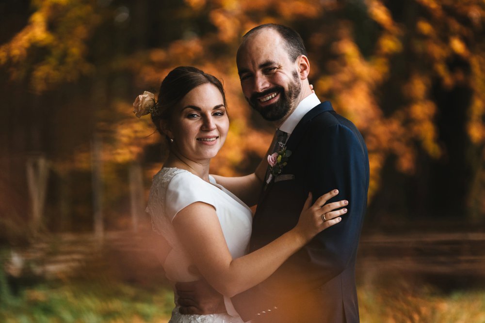 Brautpaar blickt in die Kamera bei einem Brautporträt im Herbstlaub