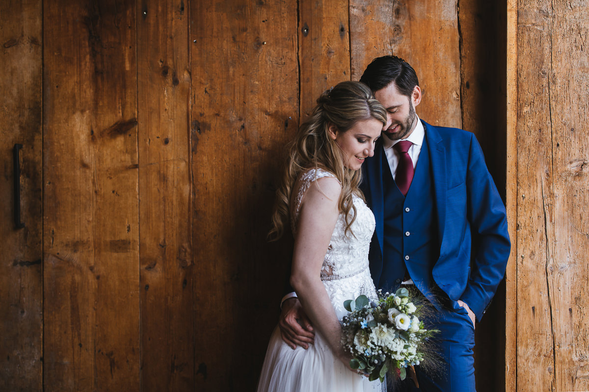 Brautpaar vor einer rustikalen Scheunenwand beim Hirzinger